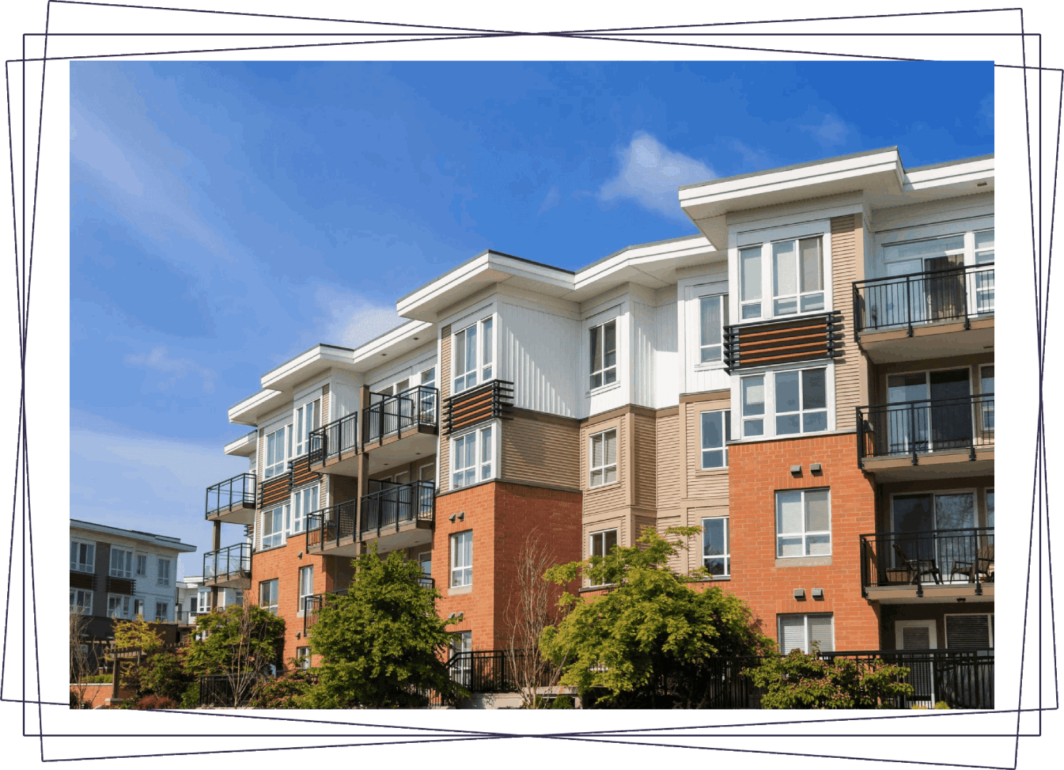 A row of apartment buildings with trees in front.